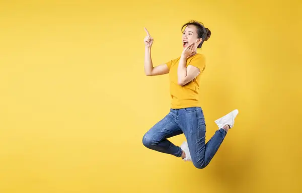 一个快乐的女孩在黄色背景下独自跳起来的全长肖像 — 图库照片