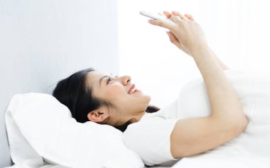 Sabah, yatakta telefon kullanan bir kızın görüntüsü.