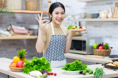 Mutfakta salata hazırlayan Asyalı bir kadın resmi.