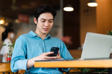 Asyalı adam oturuyor ve kahve içiyor.