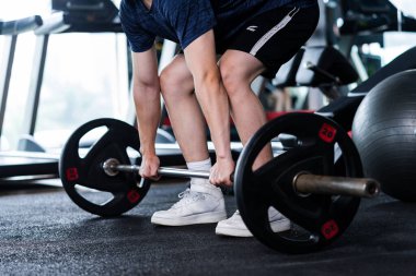 Spor giyimli genç adam spor salonunda egzersiz yapıyor.