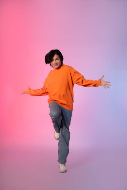 Neon renkli arka planda dans eden genç bir Asyalı resmi