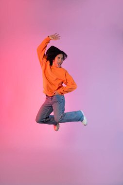 Neon renkli arka planda dans eden genç bir Asyalı resmi