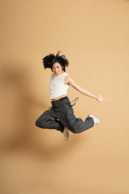 Bej arka planda dans eden Asyalı dansçı görüntüsü