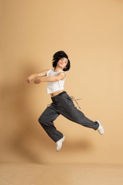 Bej arka planda dans eden Asyalı dansçı görüntüsü