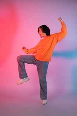 Neon renkli arka planda dans eden genç bir Asyalı resmi