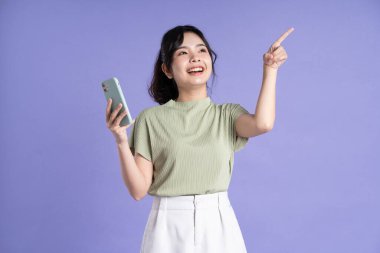 Mor arka planda akıllı telefon kullanan güzel Asyalı kadın portresi