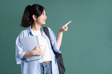 Yeşil arka planda güzel bir Asyalı öğrencinin portresi.