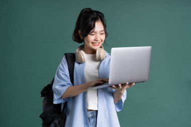 Yeşil arka planda güzel bir Asyalı öğrencinin portresi.