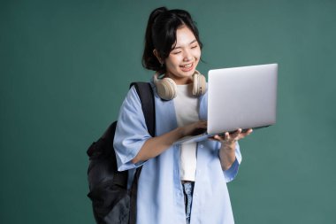 Yeşil arka planda güzel bir Asyalı öğrencinin portresi.