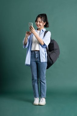 Yeşil arka planda güzel bir Asyalı öğrencinin portresi.