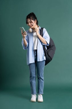 Yeşil arka planda güzel bir Asyalı öğrencinin portresi.