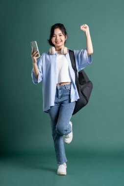 Yeşil arka planda güzel bir Asyalı öğrencinin portresi.