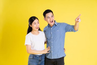 Asyalı bir çiftin sarı arka planda poz vermesi