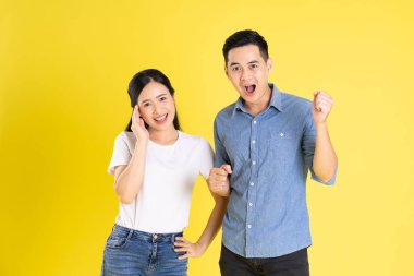 Asyalı bir çiftin sarı arka planda poz vermesi
