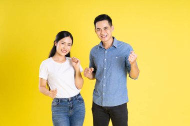 Asyalı bir çiftin sarı arka planda poz vermesi