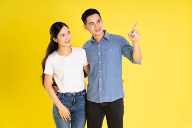 Asyalı bir çiftin sarı arka planda poz vermesi