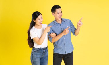 Asyalı bir çiftin sarı arka planda poz vermesi