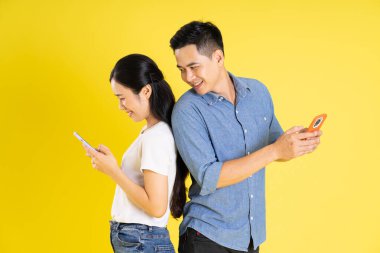 Asyalı bir çiftin sarı arka planda poz vermesi