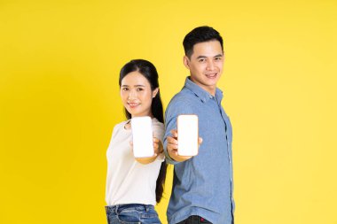 Asyalı bir çiftin sarı arka planda poz vermesi