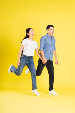 Asyalı bir çiftin sarı arka planda poz verişi.