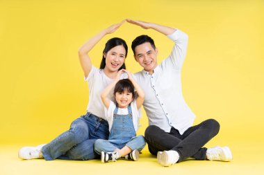 Asyalı bir ailenin sarı arka planda mutlu ve izole bir şekilde oturduğu görüntüsü