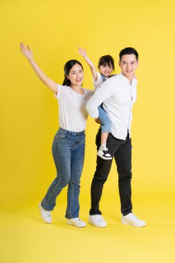 Mutlu Asyalı aile imajı, sarı arka planda izole edilmiş.