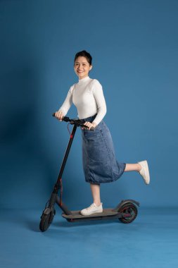 Mavi arka planda scooter süren Asyalı bir kız resmi