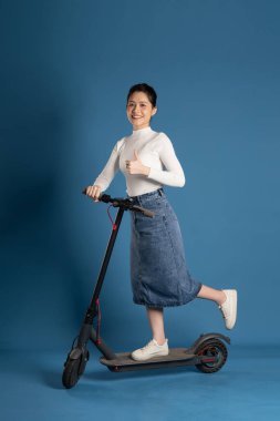 Mavi arka planda scooter süren Asyalı bir kız resmi