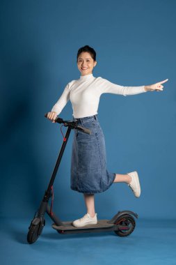 Mavi arka planda scooter süren Asyalı bir kız resmi