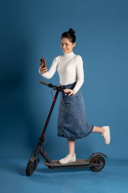 Mavi arka planda scooter süren Asyalı bir kız resmi