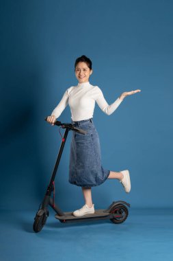 Mavi arka planda scooter süren Asyalı bir kız resmi
