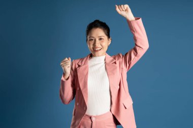 Mavi arka planda yalnız poz veren Asyalı genç iş kadını portresi