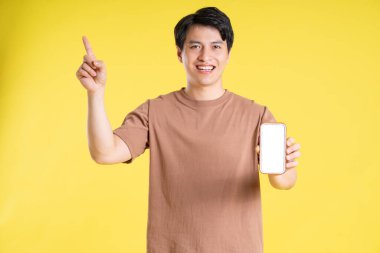 Sarı arka planda poz veren Asyalı adamın portresi