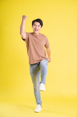 Sarı arka planda poz veren Asyalı adamın portresi