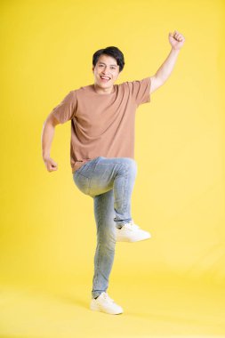 Sarı arka planda poz veren Asyalı adamın portresi