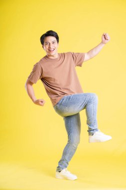 Sarı arka planda poz veren Asyalı adamın portresi