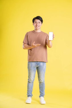 Sarı arka planda poz veren Asyalı adamın portresi