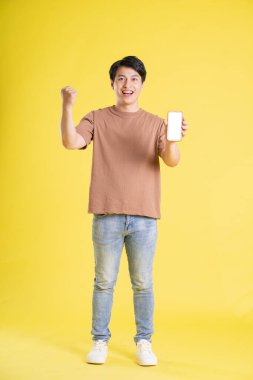 Sarı arka planda poz veren Asyalı adamın portresi