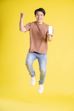 Sarı arka planda poz veren Asyalı adamın portresi