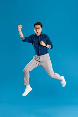 Mavi arka planda poz veren Asyalı genç iş adamının portresi