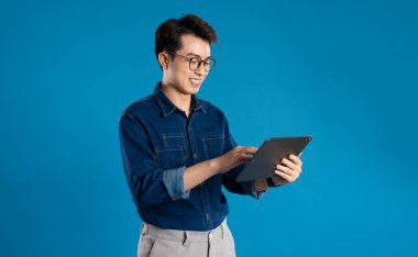 Mavi arka planda poz veren Asyalı genç iş adamının portresi