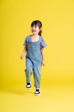 Sarı arka planda Asyalı güzel bir kızın tüm vücudu.