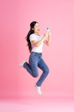 Pembe arka planda poz veren Asyalı kızın tüm vücudu.