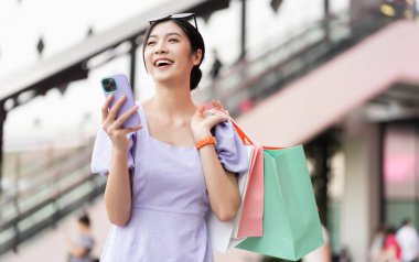 Alışveriş merkezinde mutlu Asyalı kadın alışverişi