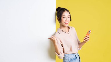 Asyalı bir kızın reklam panosuyla durup poz verişi.