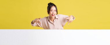 Asyalı bir kızın reklam panosuyla durup poz verişi.