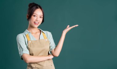 Yeşil arka planda önlük giyen Asyalı kadın portresi