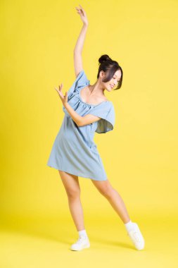 Sarı arka planda poz veren Asyalı kadın portresi