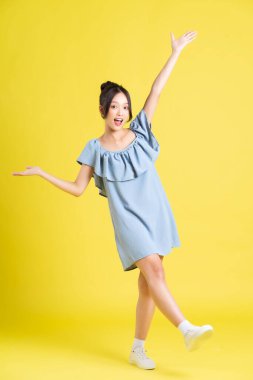 Sarı arka planda poz veren Asyalı kadın portresi